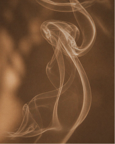 Abstract sepia-toned smoke or vapor curls against a warm brown background.