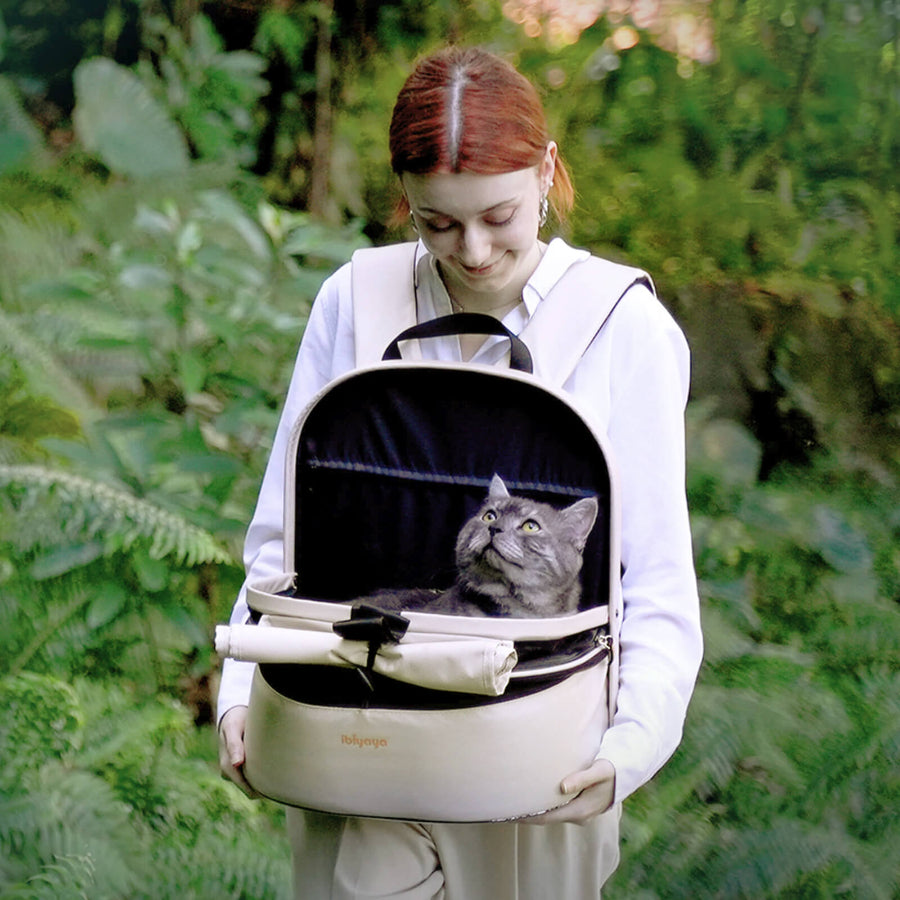 cat lover holding an Ibiyaya pet carrier on chest with a cat inside, surrounded by greenery