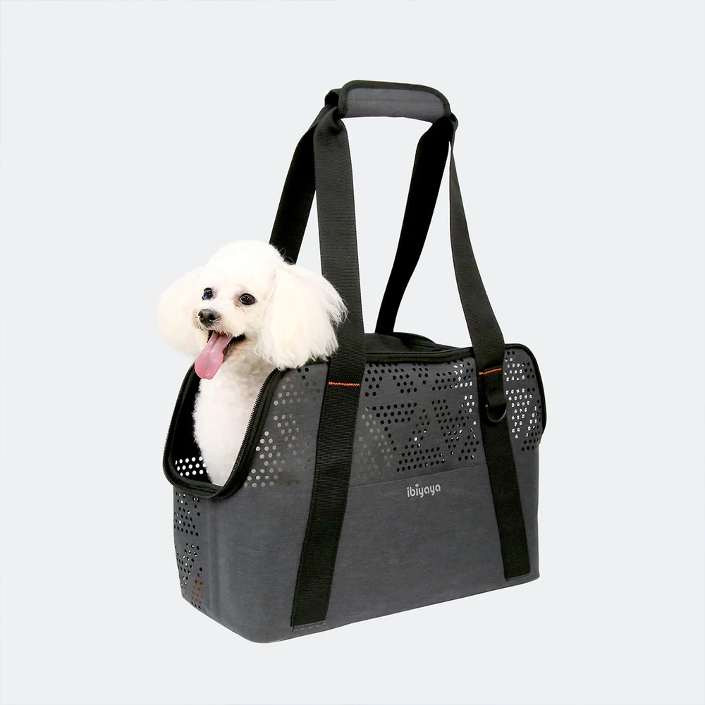 Miniature poodle dog in a gray pet carrier with Ibiyaya logo on a light gray background