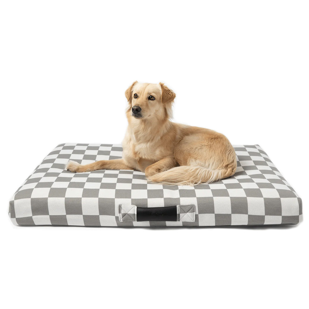 Large dog lying on a Lay lo checkered pet bed with a white background