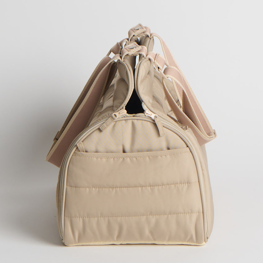 Beige pet carrier with a strap on a light gray background