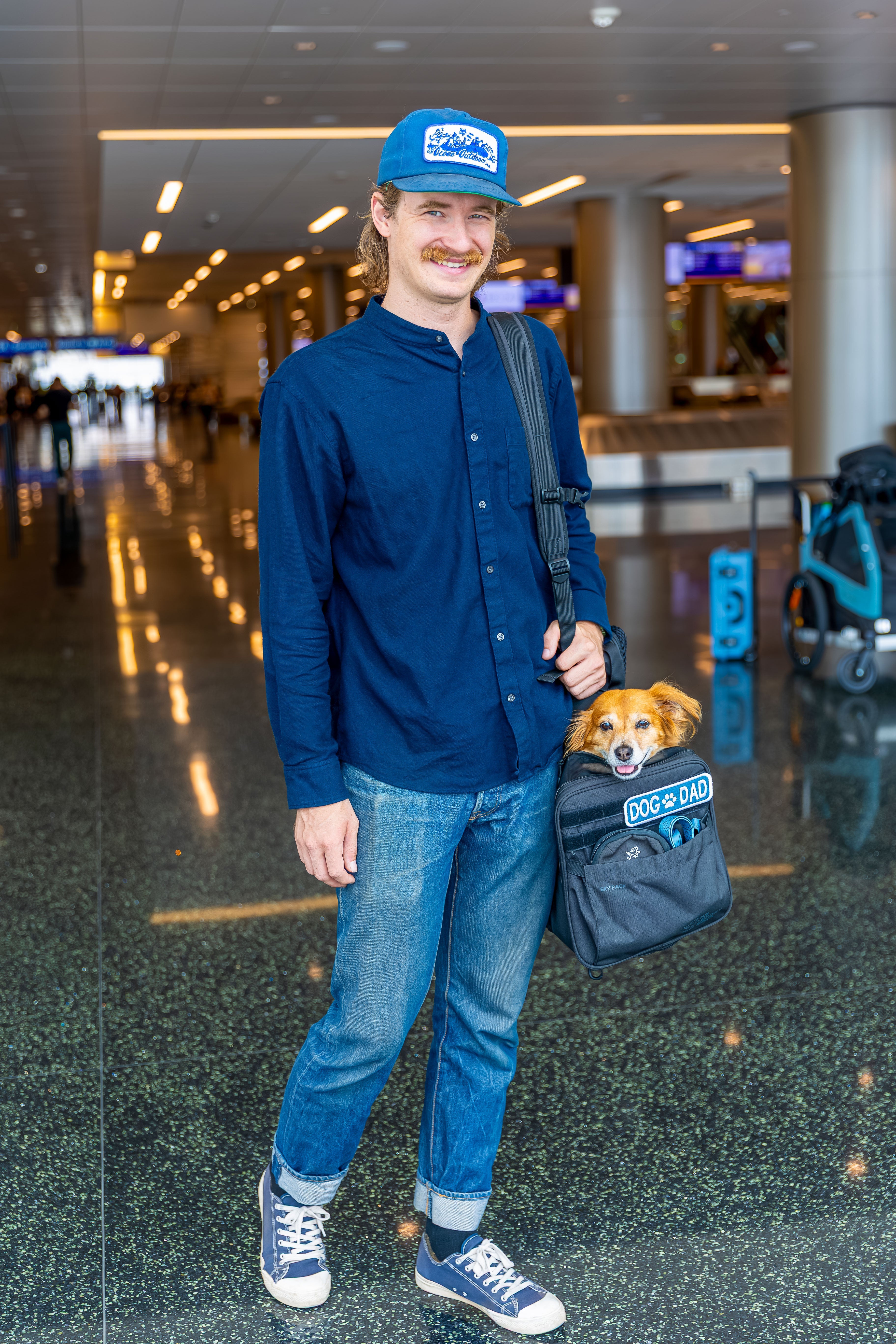 Dog owner carrying K9 Sport Sack dog backpack at the airport for airline travel safely