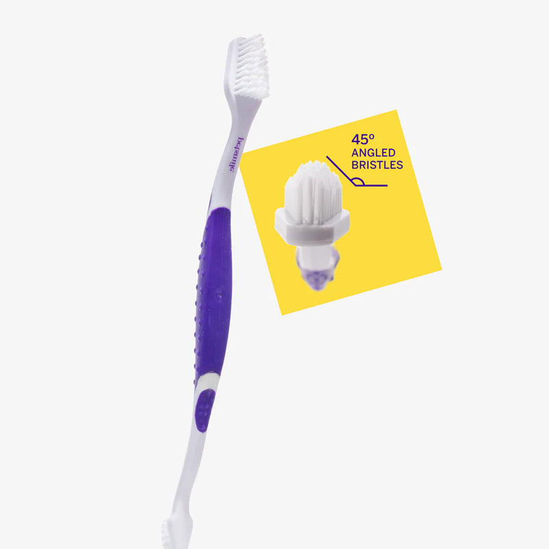 Petsmile pet toothbrush with purple handle and white bristles next to a yellow card with text on a white background