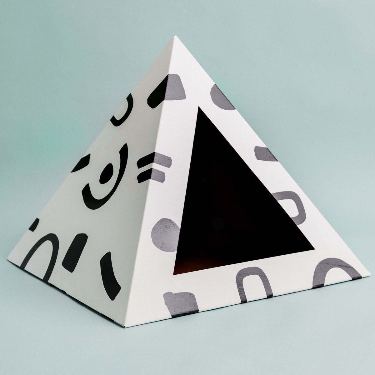 Triangular pyramid cat box with geometric pattern on a light blue background