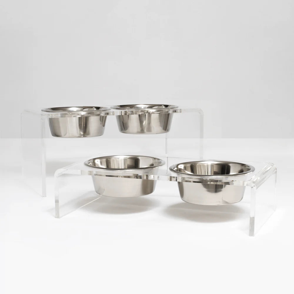 Set of four stainless steel bowls on a clear stand against a white background