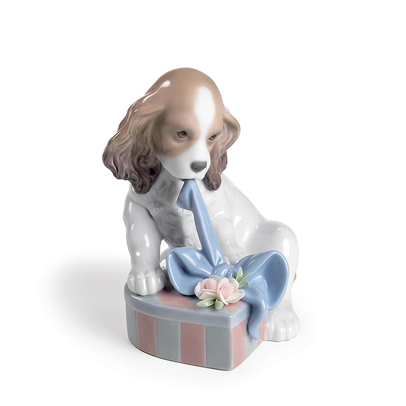 Lladro puppy figurine trying to open a gift package and ribbon
