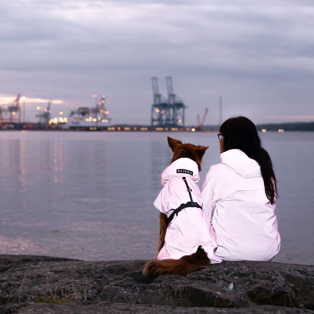 Dog and dog owner sitting by the lake with matching clothing from Paikka waterproof raincoats collection