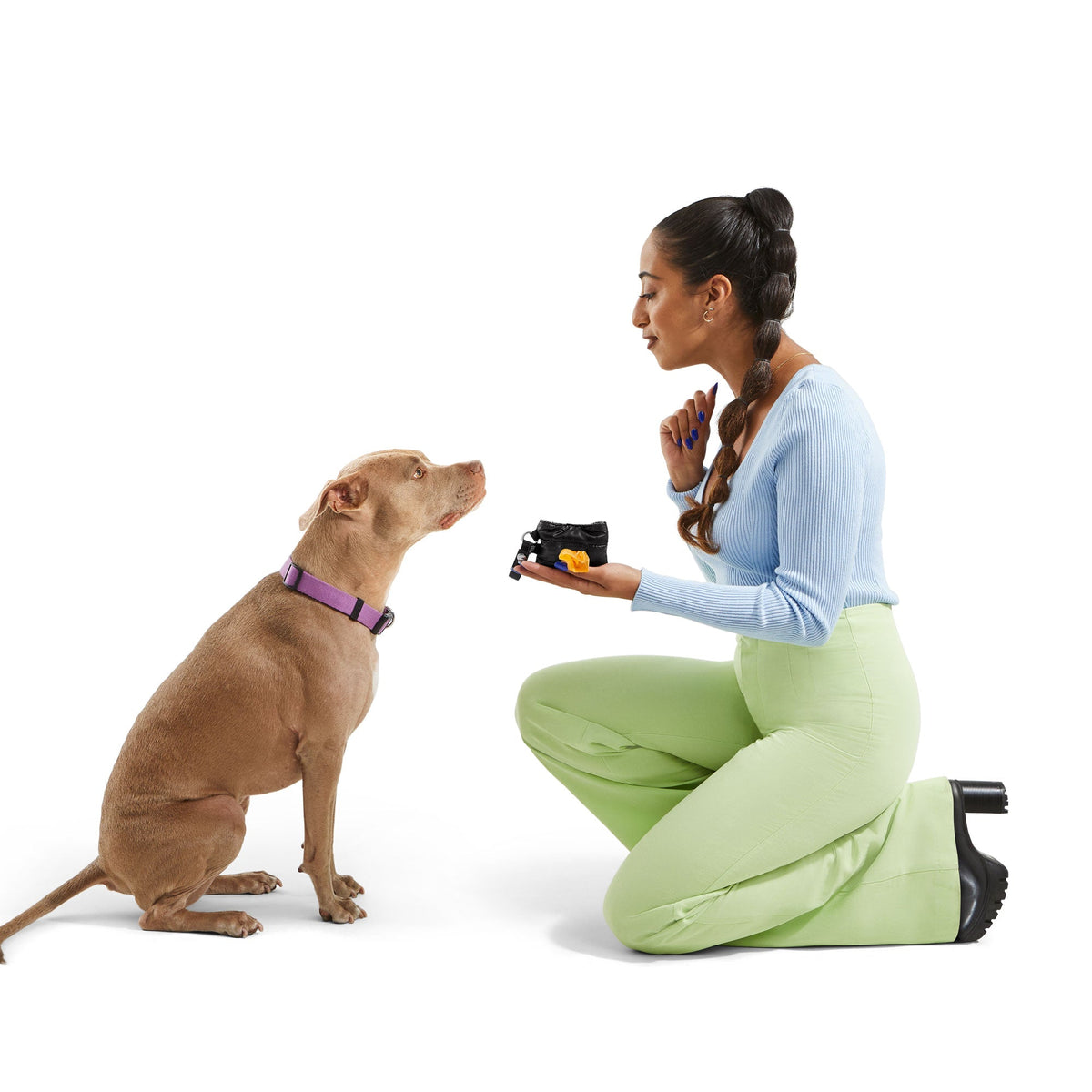 Woman giving her dog a treat with the JUST FRED waste bag pouch on the leash