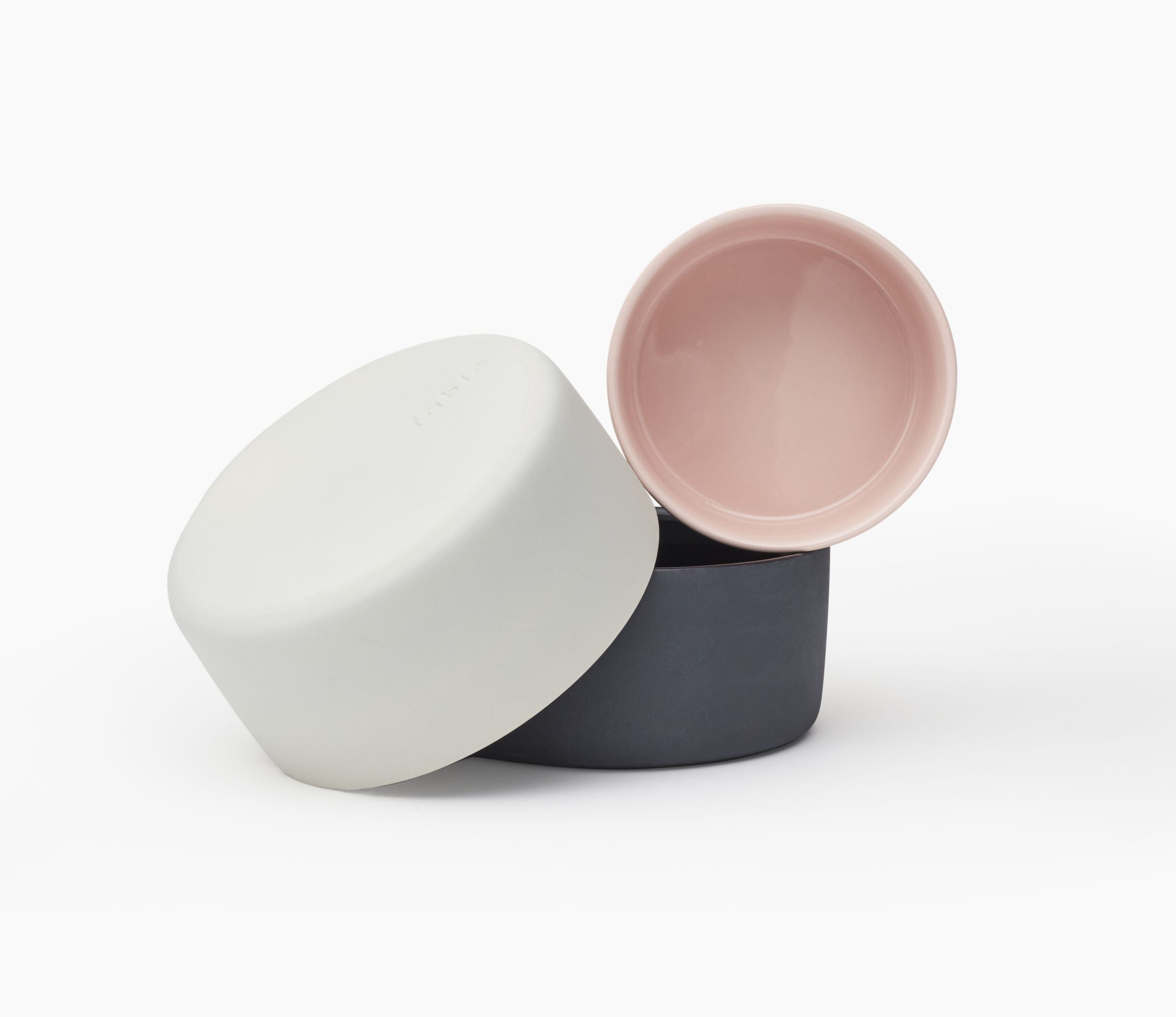 Set of three ceramic pet bowls in white, pink, and gray on a white background