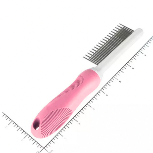 Pink pet grooming comb with metal teeth on a white background with a ruler for scale.