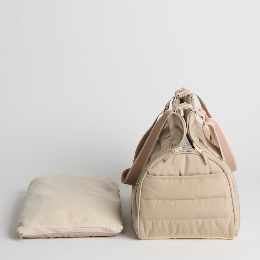 Beige pet carrier and pillow on a light gray background