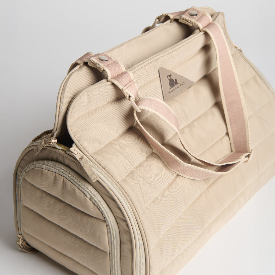 Beige pet carrier with pink handle on a light gray background