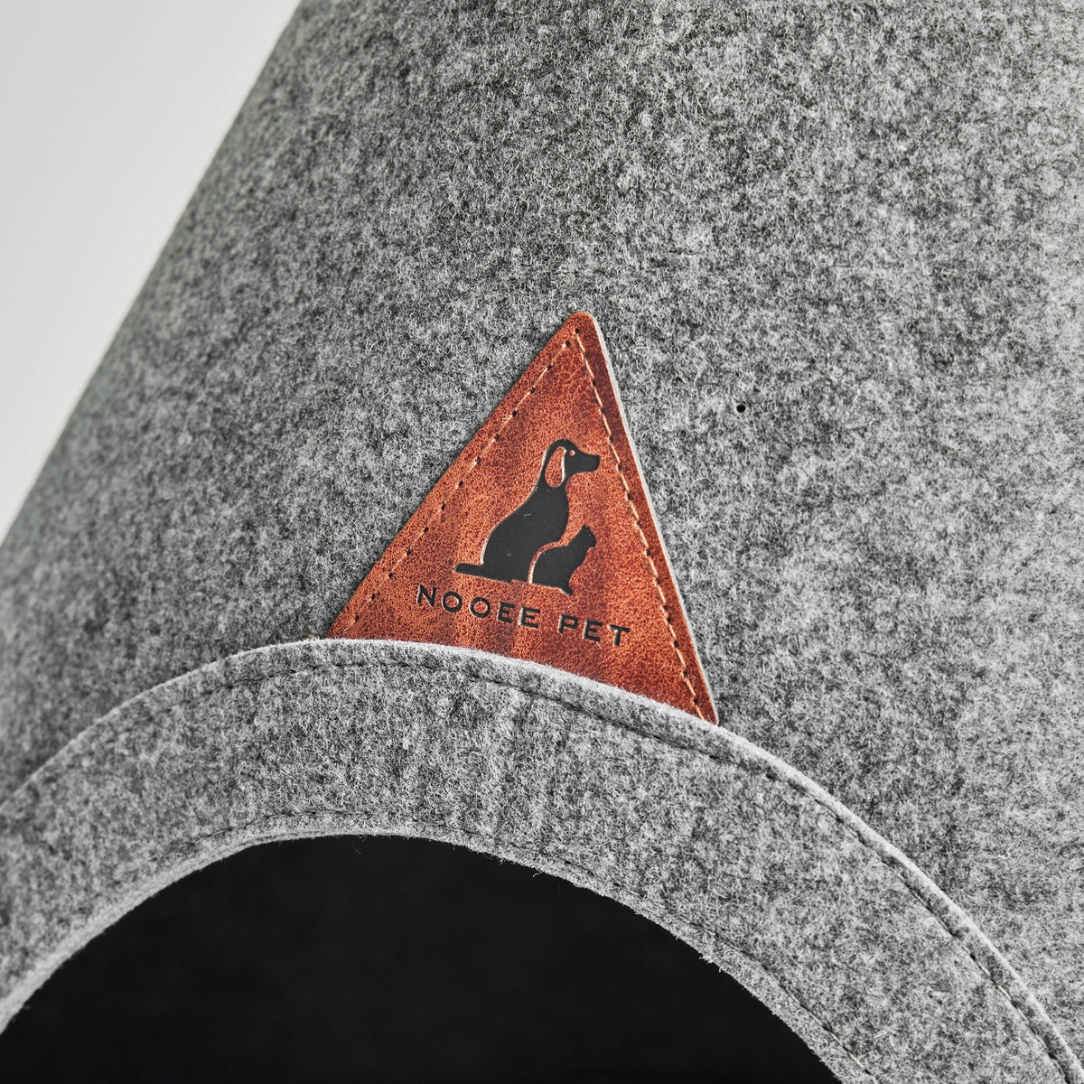 Close-up of the Nooee logo patch above the door of the Harry XXL pet cave in gray