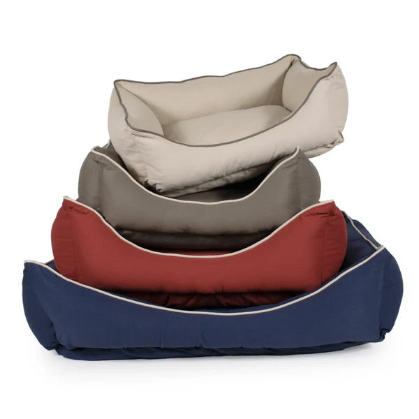 Stack of four canvas dog beds in beige, gray, red, and navy on a white background