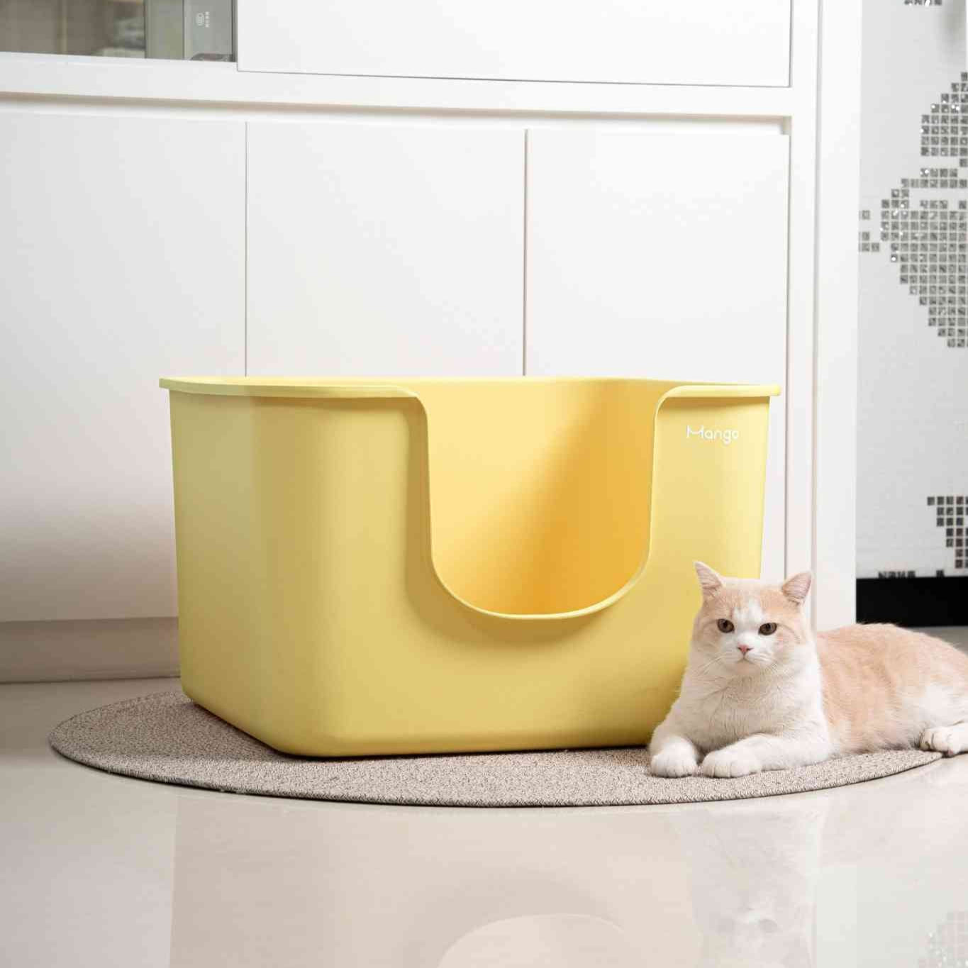 Yellow XXL cat litter box with a cat lying on a rug in a modern room.