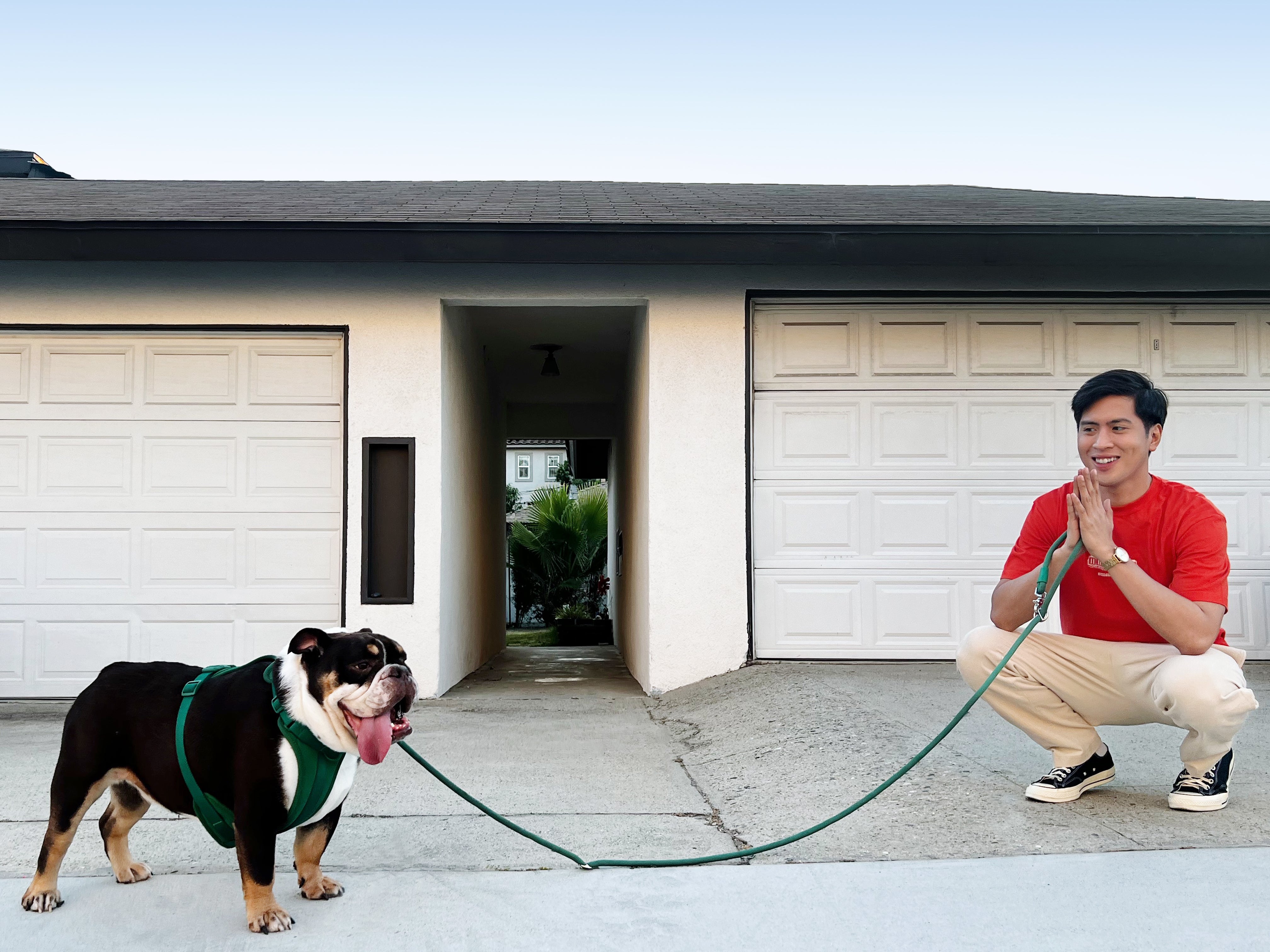 Man with a bulldog on a long leash in front of a garage