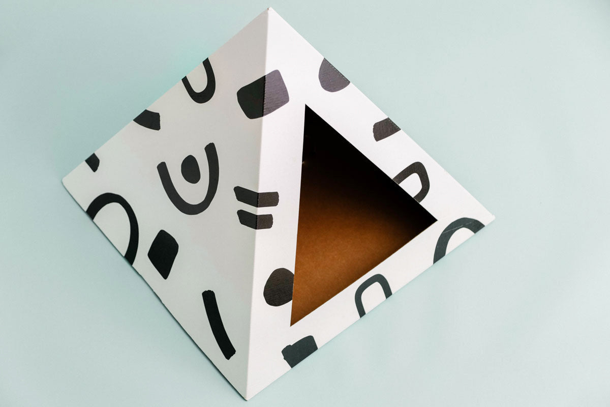 Geometric cardboard box for cats with abstract black patterns on a light blue background