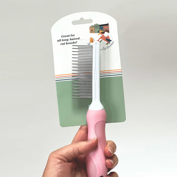 Pink long air cat pet comb held by a hand for detangling