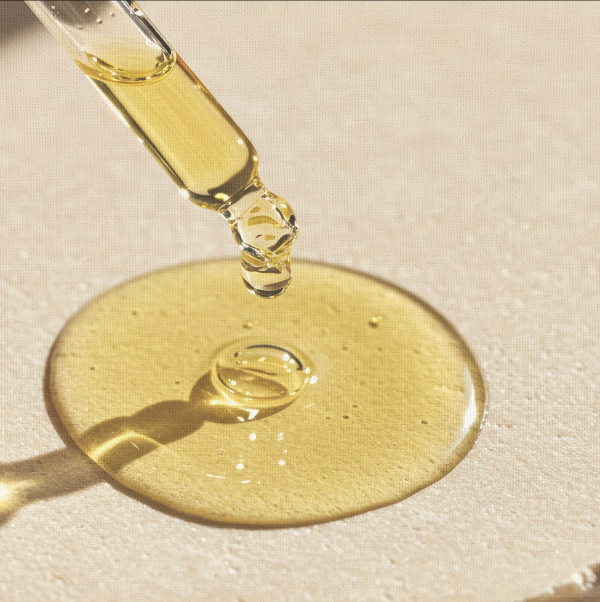 Yellow liquid being dripped from a dropper onto a beige surface