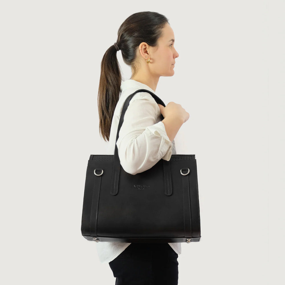 Woman carrying a black handbag for toy breed dogs on a light gray background