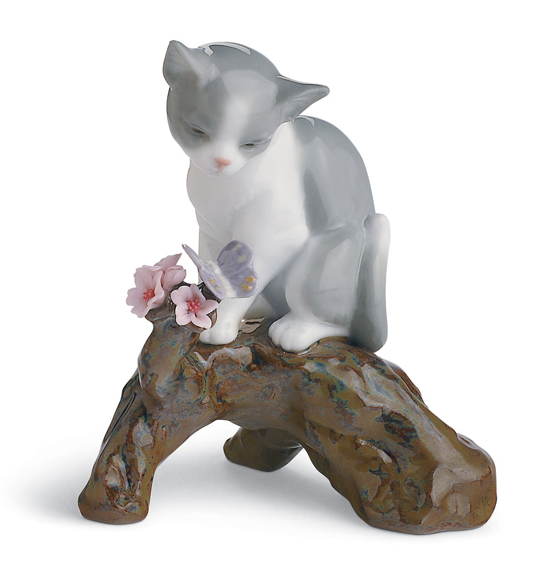 Lladro cat sitting on tree bench with flowers