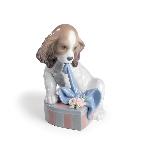 Lladro puppy figurine trying to open a gift package and  ribbon