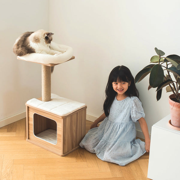 Girl sitting with her cat next to a stylish cat scratcher from catry brand