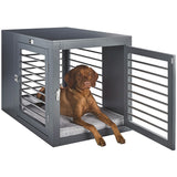 Vizsla ldog sitting in stylish large size dog crate as furniture side table.